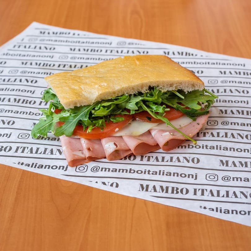 A Mambo Italiano sandwich with mortadella, cheese, tomatoes, and arugula on focaccia bread.